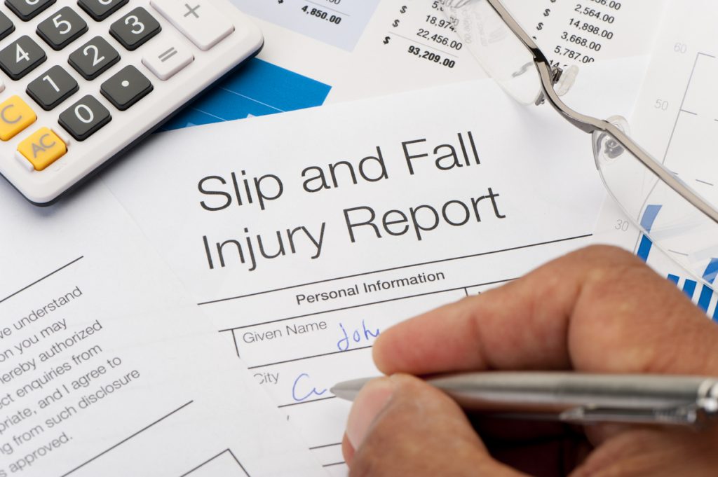 Close up of Slip and Fall injury Form with pen, calculator and writing hand